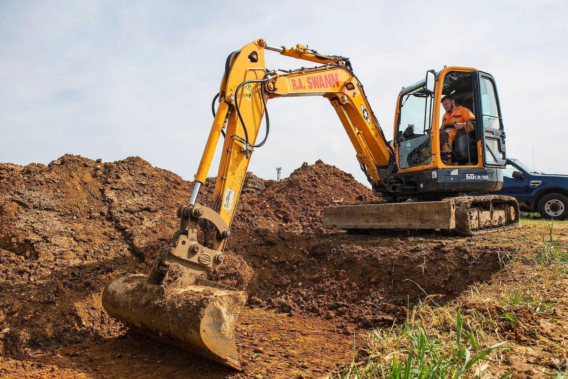 Excavator digging and shaping a new farm pond on rural acreage in Northwest Arkansas